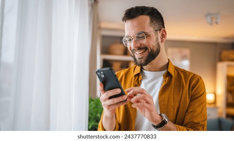 one man adult caucasian male use mobile phone smartphone at home for online web internet search or sms text messages texting  - Powered by Shutterstock