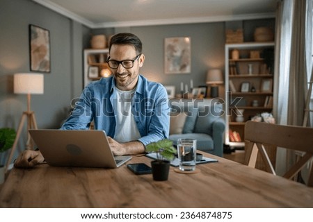 one man adult caucasian male with beard work on his laptop computer at home happy smile success freelance entrepreneur or remote work concept