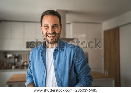 One man adult portrait of caucasian male with beard and eyeglasses stand at home happy smile copy space