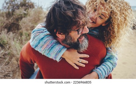 One man carry overjoyed woman in piggyback in outdoor leisure activity together having fun and laughing a lot. Happy mature people youth inside enjoy relationship and friendship carrying on the back - Powered by Shutterstock