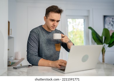 One Man Caucasian Young Adult Male In The Kitchen In The Morning Working On The Laptop Computer With Cup Of Coffee Daily Routine Internet Browsing Online Search Real People Copy Space