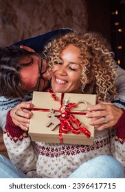 One man doing surprise gift to a woman in christmas eve night celebration. Happy couple enjoy december holiday celebration at home together with love and joy. Concept of box present and Relationship - Shutterstock ID 2396417715