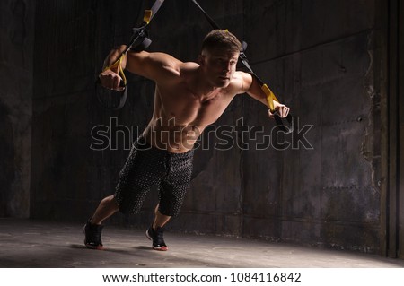 One man exercising suspension training trx on dark studio