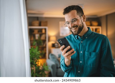 One man with eyeglasses stand at home use mobile phone sms texting - Powered by Shutterstock