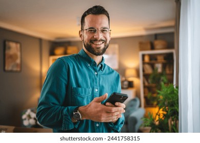 One man with eyeglasses stand at home use mobile phone sms texting - Powered by Shutterstock