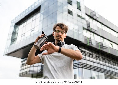 One Man Front View Portrait Of Adult Caucasian Male Athlete Or Amateur Posing In Outdoor Gym Training Park While Resting Taking A Brake From Exercise In Summer Day Checking Wristwatch Time Copy Space