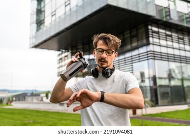 One Man Front View Portrait Of Adult Caucasian Male Athlete Or Amateur Posing In Outdoor Gym Training Park While Resting Taking A Brake From Exercise In Summer Day Checking Wristwatch Time Copy Space