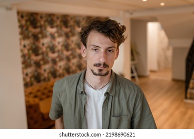 One Man Front View Portrait Waist Up Standing Indoor In Cafe Or Restaurant Lobby Happy Smile Confident Wear Olive Shirt With Modern Haircut Mustaches And Beard Looking To The Camera