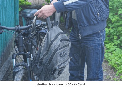 one man hangs gray backpack bag on black bicycle handlebar on spring street