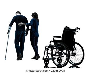 one man injured man with woman walking away from wheelchair with crutches in silhouette studio on white background