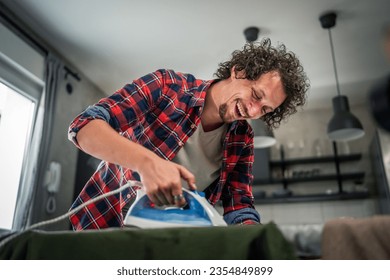 one man ironing clothes at home hold iron on shirt on board household chores concept adult male in 30s living in the apartment alone doing housework copy space - Powered by Shutterstock