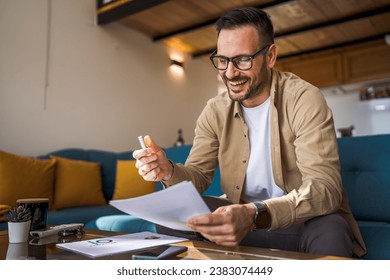 One man mature caucasian male work at home hold paper document sign insurance contract or read report enjoy good news in letter receive official paper about tax refund credit loan approval - Powered by Shutterstock