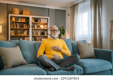 one man mature senior caucasian male using headphones for online guided meditation practicing mindfulness yoga manifestation with eyes closed at home real people self care concept copy space