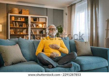one man mature senior caucasian male using headphones for online guided meditation practicing mindfulness yoga manifestation with eyes closed at home real people self care concept copy space