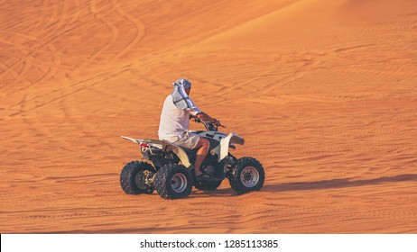 One Man On Quad Bike ATV Exploring Desert Alone With Head Covered By Keffiyeh. Adventure Concept With Tourist Discover Earth On Quad Biking Dubai Tour – Dune Bashing And Dune Buggy Activities