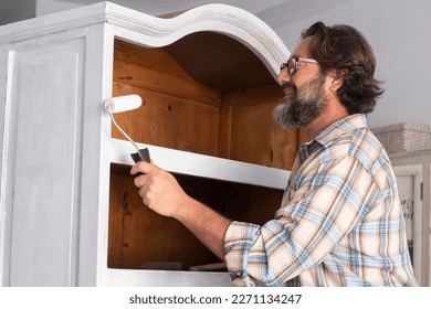 One man paint an old antique recycled cabinet at home in happy hobby indoor leisure activity alone. Concept of renovating and recycling sustainable. New home beginnings lifestyle male people - Shutterstock ID 2271134247