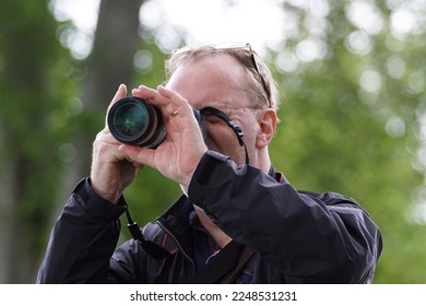 One man photographing through a camera outdoors  - Shutterstock ID 2248531231