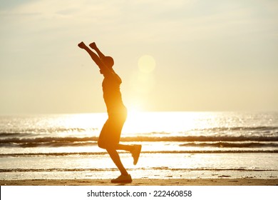 One man running on beach with arms raised in celebration - Powered by Shutterstock