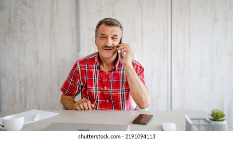 One Man Senior Entrepreneur Active Caucasian Male Making A Phone Call Talking While Sitting At The Desk Table Working At Office Manager And Small Business Real People Copy Space