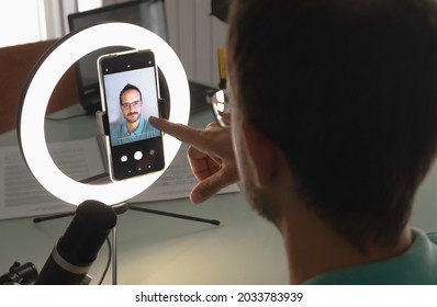 One Man Setting Up A Video Call With His Smart Phone And A Light Ring Studio Lamp