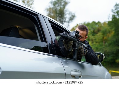 One Man Special Force Police Or Terrorist Holding Automatic Weapon Shooting And Aiming From The Car Anti-terrorist Unit On The Mission Under Attack In Vehicle Copy Space Side View