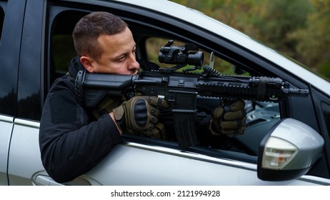 One Man Special Force Police Or Terrorist Holding Automatic Weapon Shooting And Aiming From The Car Anti-terrorist Unit On The Mission Under Attack In Vehicle Copy Space Side View