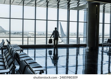 One man standing at the airport gate waiting his flight with delay or canceled. Traveler people lifestyle in indoor leisure activity. One tourist with backpack wait to fly with airplane for vacation