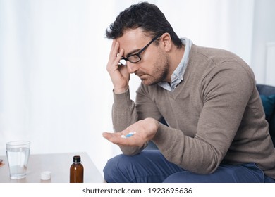 One man taking painkillers to relieve pain and headache - Shutterstock ID 1923695636