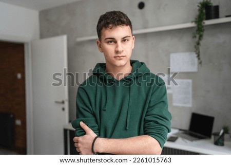 one man teenager stand in room at home wear green hoodie waist up