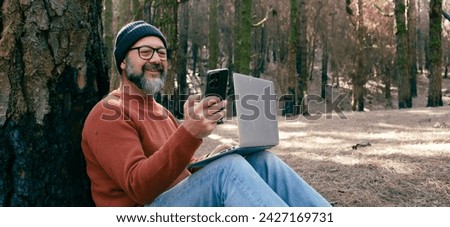 One man using phone cellular connection in a forest wood enjoying technology and outdoor leisure activity. Modern man speaking at cellular with trees in background. People and communication on travel