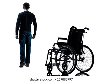 one man walking away from wheelchair in silhouette studio on white background