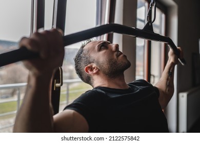 One man young adult caucasian male bodybuilder training back on the cable machine in the gym wearing shirt dark photo real people copy space side view