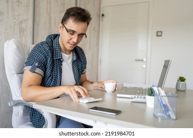 One Man Young Adult Caucasian Male Sitting At Desk In The Office At Work Using Calculator To Calculate Project And Finance Real People Copy Space