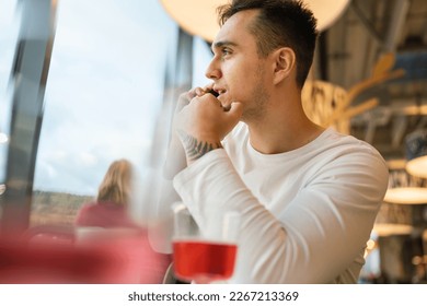 One man young adult caucasian male sit at cafe or restaurant using mobile phone making a call talk real people copy space serious worried - Powered by Shutterstock