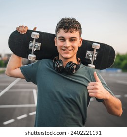 One man young adult caucasian teenager stand outdoor with skateboard on his shoulder and headphones posing at basketball court portrait happy confident wear shirt casual real person copy space - Powered by Shutterstock