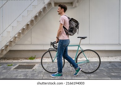 One Man Young Adult Male With Brown Hair And Mustaches Walking By The Building With Rucksack On His Back And Bicycle Happy Smile Joyful Real People Copy Space Side View Full Length