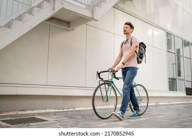 One Man Young Adult Male With Brown Hair And Mustaches Walking By The Building With Rucksack On His Back And Bicycle Happy Smile Joyful Real People Copy Space Side View Full Length