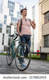 One Man Young Adult Male With Brown Hair And Mustaches Walking By The Building With Rucksack On His Back And Bicycle Happy Smile Joyful Real People Copy Space Side View