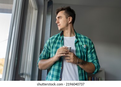 One Man Young Adult Male Caucasian With Brown Hair Stand At Window At Home In Morning Day Confident Looking To The Side Serious Confident Wear Green Shirt Hold Cup Of Coffee Copy Space Daily Routine