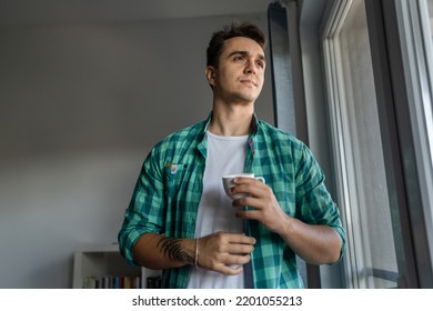 One Man Young Adult Male Caucasian With Brown Hair Stand At Window At Home In Morning Day Confident Looking To The Side Serious Confident Wear Green Shirt Hold Cup Of Coffee Copy Space Daily Routine