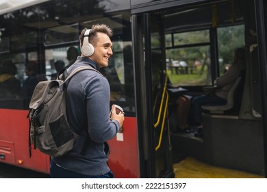 One man young adult male stand at public transport bus station taking bus with headphones and mobile smart phone in winter or autumn day with backpack student or tourist city life copy space - Powered by Shutterstock