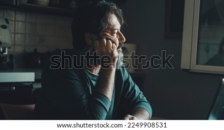 One mature man at home witting worried at the table with stress and depression Concept of life problems and worried people. Adult man looking for solutions at home. Sadness and loneliness condition
