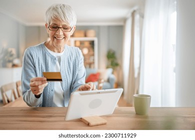 One mature senior woman grandmother sit at home use credit or debit card for online shopping browse internet stores buying stuff real people copy space - Powered by Shutterstock