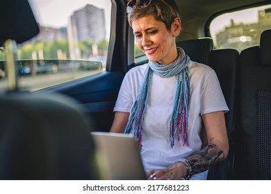 One Mature Woman Caucasian Female Sitting On The Back Seat Of The Car Working On Laptop Computer In Summer Day With Short Gray Hair Modern Manager Or Business Owner On Road Wearing Casual Copy Space