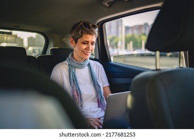 One Mature Woman Caucasian Female Sitting On The Back Seat Of The Car Working On Laptop Computer In Summer Day With Short Gray Hair Modern Manager Or Business Owner On Road Wearing Casual Copy Space