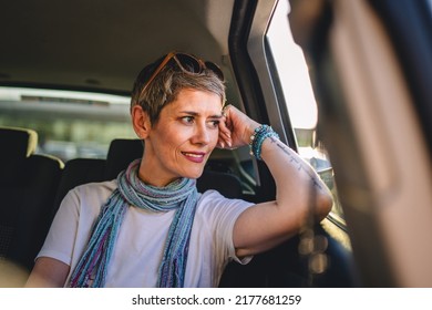 One mature woman caucasian female sitting on the back seat of the car looking trough the glass window in summer day happy smile travel and transport concept copy space real person gray short hair - Shutterstock ID 2177681259