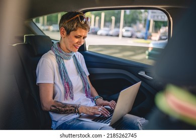 One Mature Woman Caucasian Female Sitting On The Back Seat Of The Car Working On Laptop Computer In Summer Day With Short Gray Hair Modern Manager Or Business Owner On Road Wearing Casual Copy Space