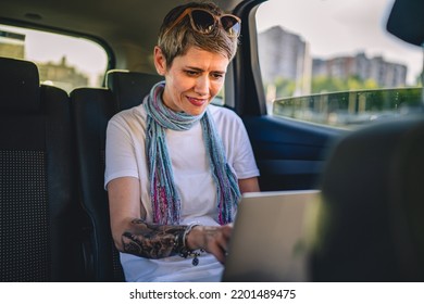 One Mature Woman Caucasian Female Sitting On The Back Seat Of The Car Working On Laptop Computer In Summer Day With Short Gray Hair Modern Manager Or Business Owner On Road Wearing Casual Copy Space