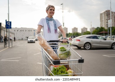 One Mature Woman Caucasian Female Walking In The Parking Lot In Front Of The Shopping Center Grocery Store Supermarket Pushing Chart Happy Smile Half Length Copy Space