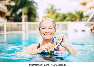 one mature woman doing activity at the pool swimming and training alone - looking at the camera ad smiling - Powered by Shutterstock